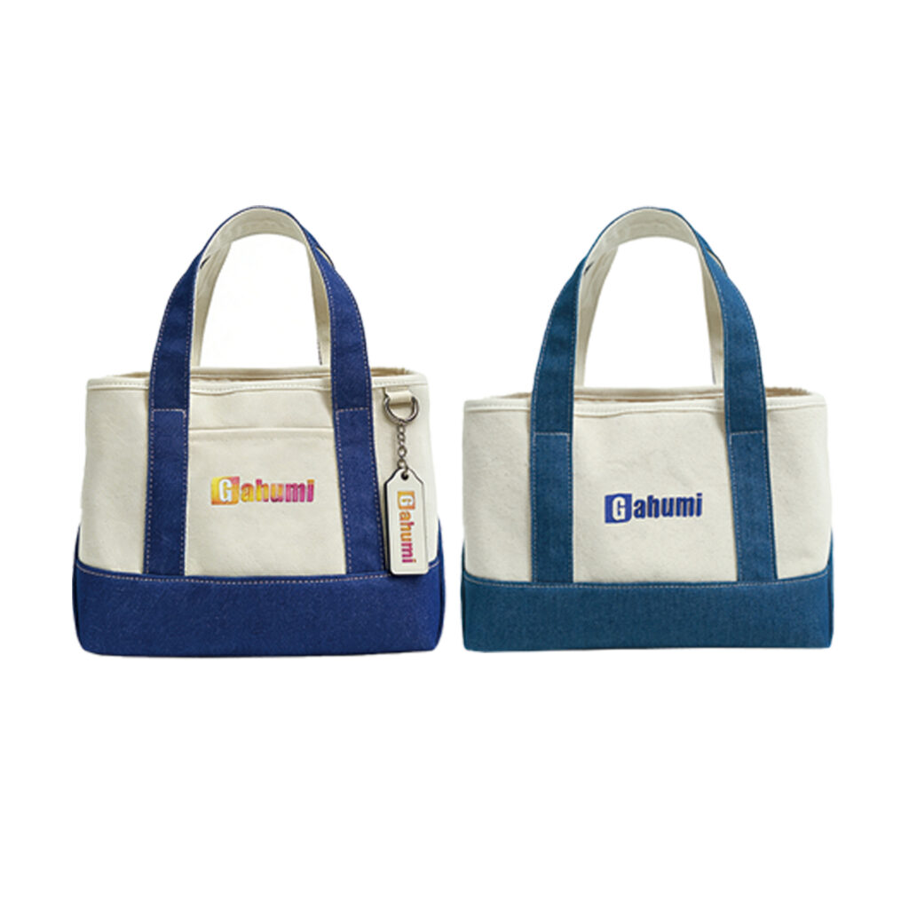 Two cream Gahumi tote bags with blue handles and base panels, one with a hanging tag